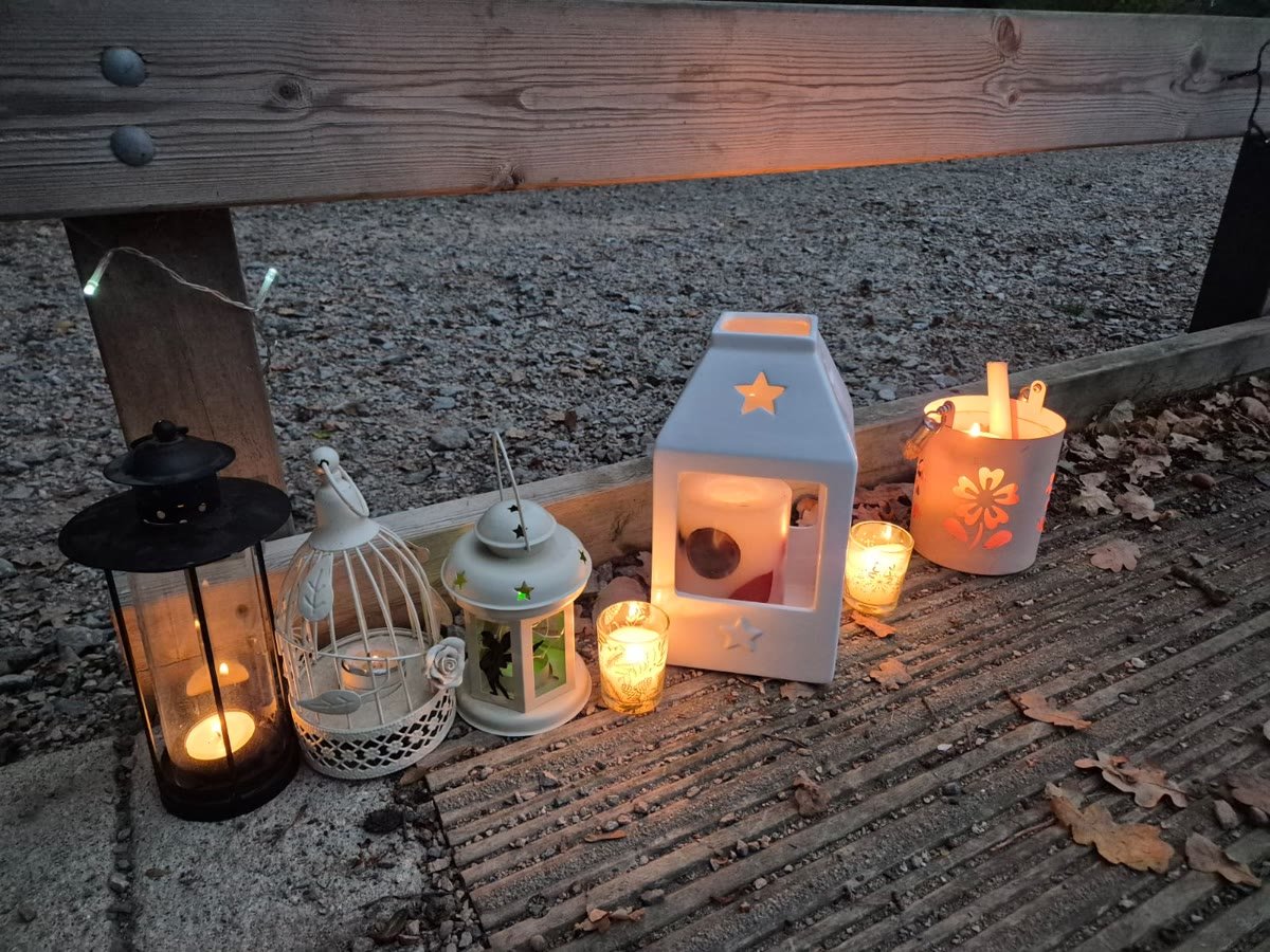 Candles glowing in lanterns on the wooden platform at dusk